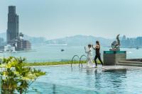 a man and woman standing next to a swimming pool at Four Seasons Hotel Hong Kong in Hong Kong