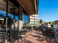 an empty patio with tables and chairs outside a building at HOTEL MYSTAYS Matsuyama in Matsuyama