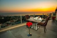 a table and chairs on a balcony with a sunset at Maximus Hotel Byblos in Jbeil