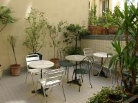 a patio with tables and chairs and potted plants at Hotel Darcet in Paris