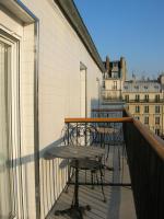 a balcony with tables and chairs on a building at Hotel Darcet in Paris