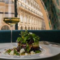 a plate of food on a table with a glass of wine at Galleria Vik Milano - Townhouse Galleria - Small Luxury Hotels of the World in Milan