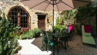 a patio with a table and chairs with an umbrella at Au coeur de Beynac, une maison de caractère avec jardin terrasse in Beynac-et-Cazenac