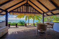 a patio with a table and chairs and the ocean at Tamanu Beach in Arutanga