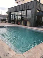 a swimming pool in front of a building at The Originals City, Hôtel Hélios, Roanne Nord (Inter-Hotel) in Mably