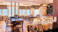 a dining room with tables and chairs and windows at Hôtel Le Beaufort in Saint Malo