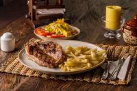 uma mesa com dois pratos de carne e batatas fritas em Hotel Finca Buenos Aires Barichara em Barichara