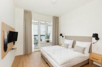 ein weißes Schlafzimmer mit einem Bett und einem Fernseher in der Unterkunft Aquamarina Onyx Marina Invest in Misdroy