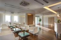 una sala de espera con sillas blancas, mesas y ventanas en Best Western Hotel San Marco, en Siena