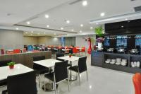 a restaurant with white tables and chairs and a kitchen at Goodness Plaza Hotel in Taishan