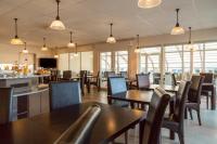 een eetkamer met tafels en stoelen en ramen bij The Originals Boutique Hôtel Spa Beuzeville Honfleur Sud in Beuzeville