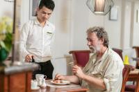 Vision Premier Hotel & Spa في هانوي: رجل يجلس على طاولة مع رجل يأكل الطعام