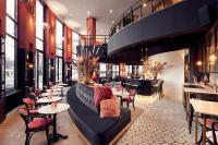 une femme assise sur un canapé dans un restaurant dans l'établissement Van der Valk TheaterHotel De Oranjerie, à Ruremonde