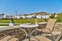a table and chairs on a stone wall with a glass of wine at Jewel Apartments Mykonos in Ornos