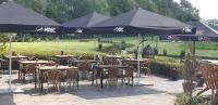 um grupo de mesas e cadeiras com guarda-sóis em Country Lodge Hotel Moriaanshoofd em Oudenaarde