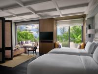 a bedroom with two beds and a television and a patio at Rosewood Phuket in Patong Beach