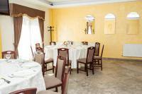 a dining room with tables and chairs and a cross on the wall at Magic Garden by Vlăduț in Bacău