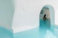a woman in the water in a swimming pool at Aspaki by Art Maisons in Oia