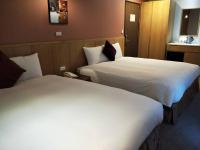 two beds in a hotel room with white sheets at In Young Hotel in Kaohsiung