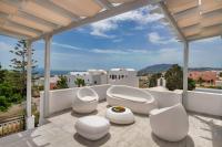 Un balcón con sillas blancas y vista a una ciudad. en Villa Soula, en Fira