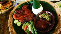 Un plato de comida con carne y verduras encima. en Sunsethouse Lombok, en Senggigi 