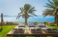 una persona sentada en una terraza con sillas y el océano en Ein Gedi Kibbutz Hotel, en Ein Gedi