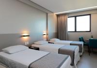a hotel room with three beds and a window at Porto Kaeté Hotel in Maceió