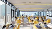 a restaurant with yellow chairs and tables and windows at Grand Ocean Luxury Boutique - Infinity Rooftop Pool in Da Nang