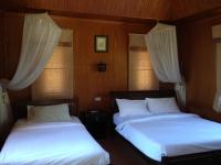 two beds in a room with white sheets and curtains at Malibu Beach Bungalows in Chaloklum