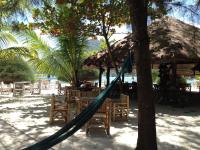 a hammock on a beach with tables and chairs at Malibu Beach Bungalows in Chaloklum