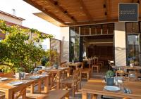 un restaurante al aire libre con mesas y sillas de madera en Basilico Suites Adults Only by Estia, en Gouves