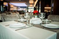 un tavolo con piatti e bicchieri e un fiore rosso di Seraphine Plaza a Pejë