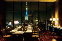 a dining room with a view of the shard at night at The Gate Hotel Kaminarimon by Hulic in Tokyo