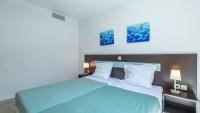 a bedroom with a blue bed with two pictures on the wall at Vacancéole - Résidence Le Crystal in Cagnes-sur-Mer