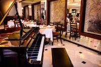 カンペチェにあるHotel Plaza Campecheのテーブルと椅子のあるレストランのピアノ