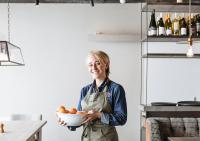 a woman in a kitchen holding a bowl of oranges at Langley Hôtel Tignes 2100 in Tignes