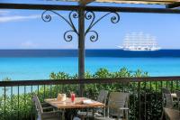 a table and chairs on a balcony with a view of the ocean at Joseph Charles in LʼÎle-Rousse