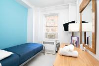 Schlafzimmer mit einem blauen Bett und einem Holztisch in der Unterkunft West Side YMCA in New York