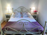 a bedroom with a bed with a purple comforter and two lamps at Hameau de Montcabirol - Foix in Mirepoix