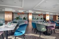 un restaurante con mesas blancas y sillas azules en Hotel In Excelsis, en Novalja