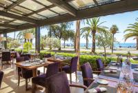 Un restaurante con mesas y sillas con el océano de fondo. en Westminster Hotel & Spa Nice, en Niza