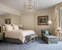 a bedroom with a bed and a chair and a chandelier at Four Seasons Hotel George V Paris in Paris