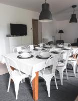 a white dining room table with white chairs and a tv at Au chalet des quatre saisons in Ax-les-Thermes