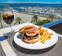 un sándwich y papas fritas en un plato con una copa de vino en Nautic Hotel & Spa, en Can Pastilla