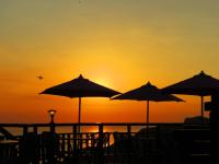 a sunset on a beach with chairs and umbrellas at Formosa Arcadian Villa in Jiufen