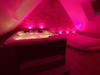 a bedroom with pink lights and a bath tub at Suite Cupidon- Domaine des trois châteaux in Moisenay