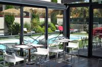 a restaurant with tables and chairs and a swimming pool at Logis Hôtel La Fauceille in Perpignan