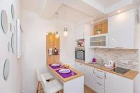 a kitchen with white cabinets and a purple plate on a counter at Apartments More in Sobra