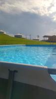 a large blue swimming pool with a green field in the background at Yurte in Langa in Bosia