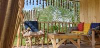 a porch with two chairs and a table and a fence at LA CABANE PERCHEE in Villelaure